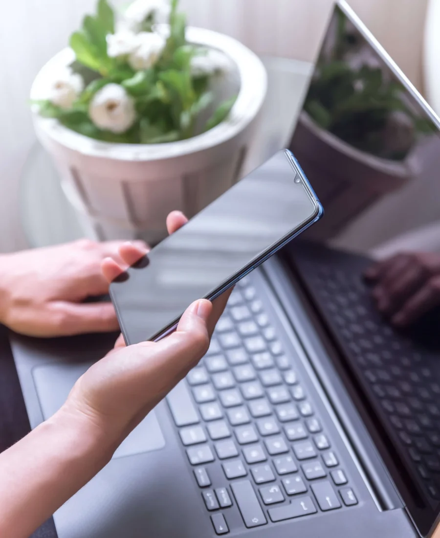 vertical-shot-female-hand-holding-smartphone-laptop_edited